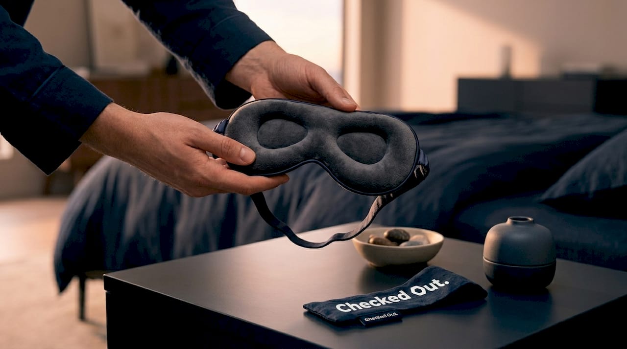 Hands holding contoured sleep mask above dresser
