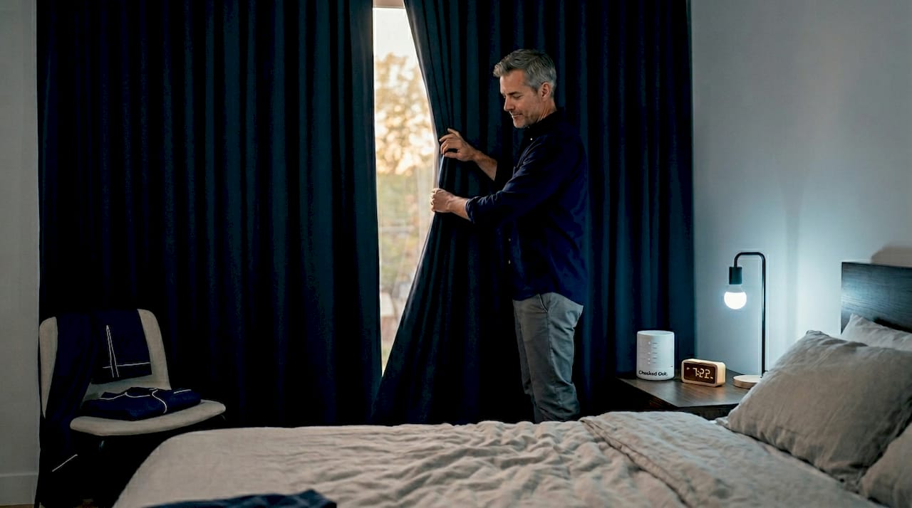 Man prepares dark bedroom for sleep