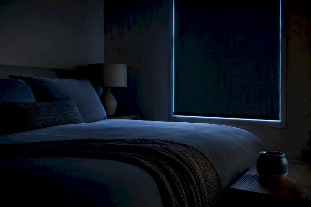 Dark bedroom with blackout shade and cool bedding