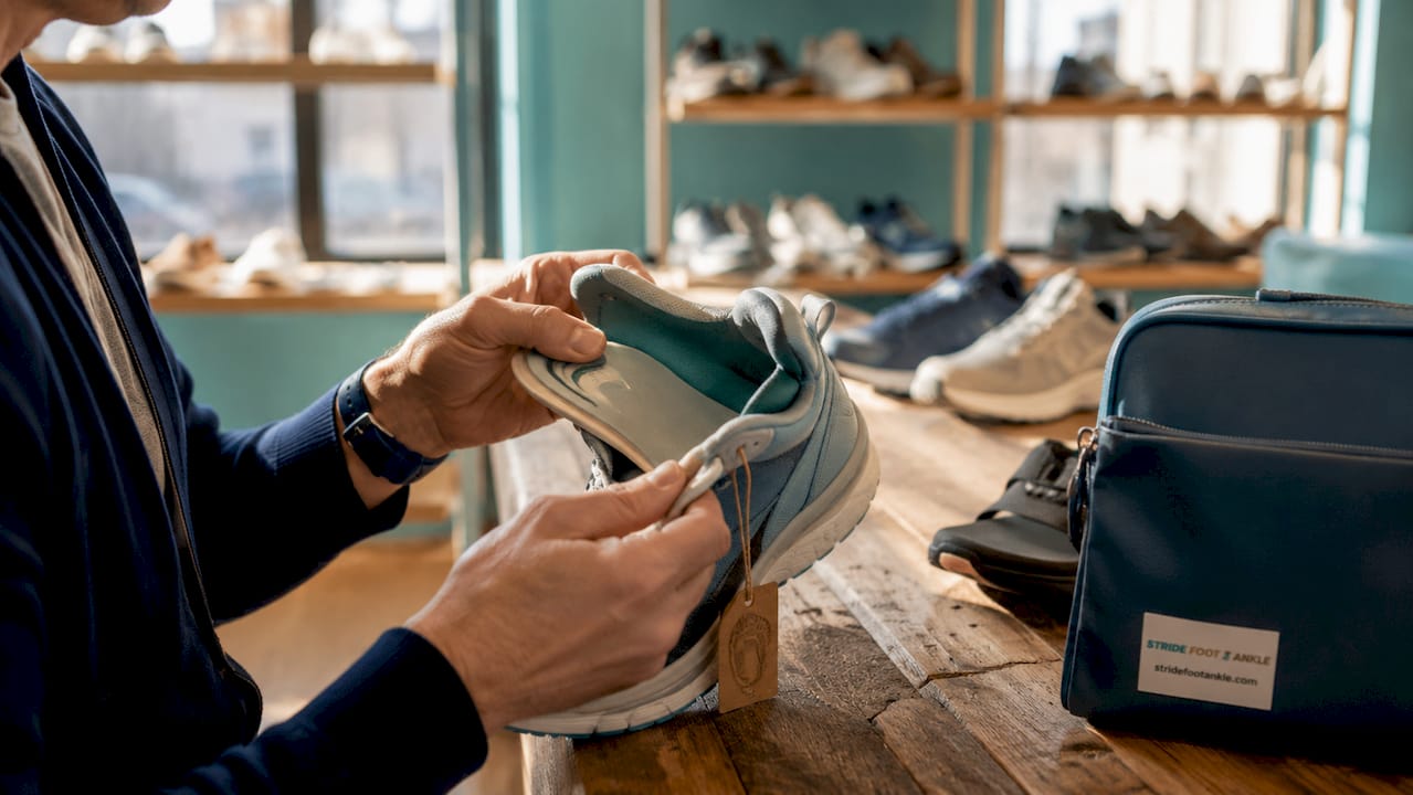 Hands holding high arch supportive shoe in store