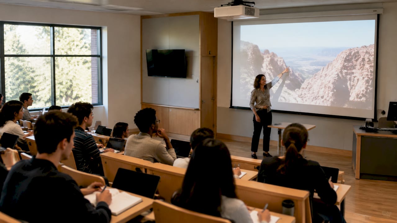 Classroom with lecturer using projector and fixed screen