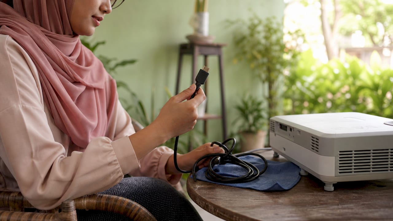 Saya sedang pegang kabel HDMI baru untuk sambungkan ke projektor.
