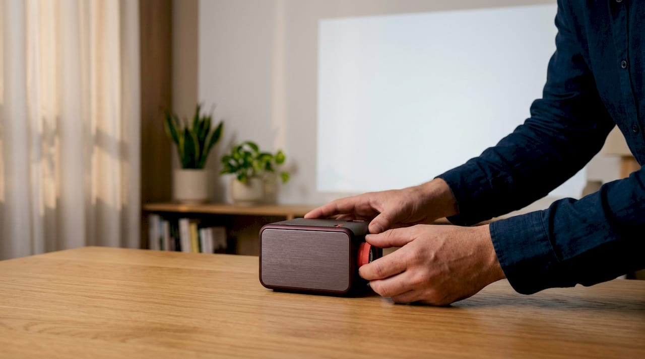 Hands adjusting mini projector on stand in office