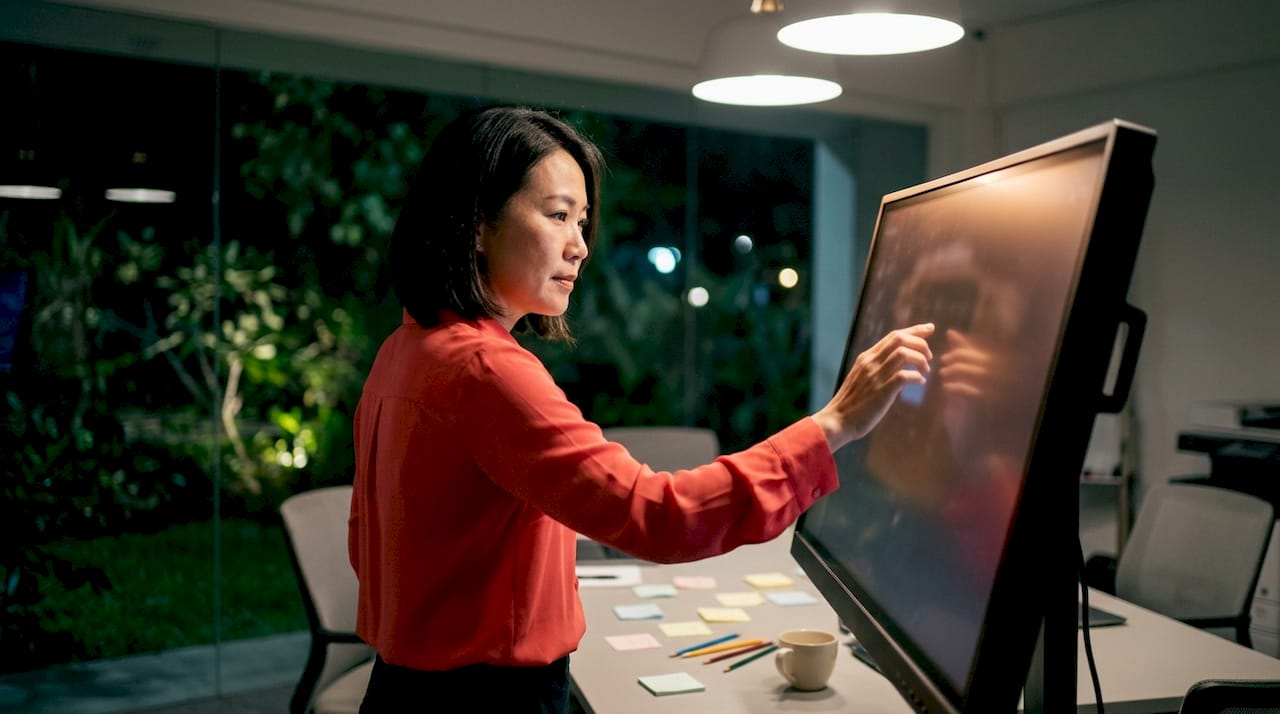 Seorang wanita sedang menggunakan skrin interaktif beresolusi 4K.