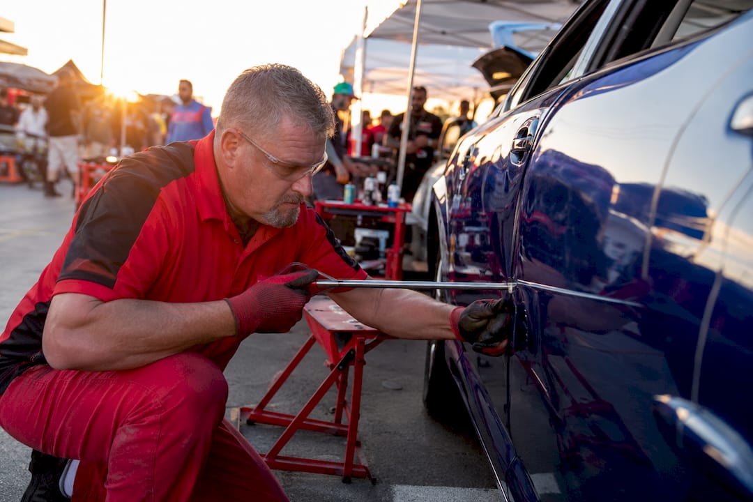 Technician Repairing Dent On Car Door In Workshop