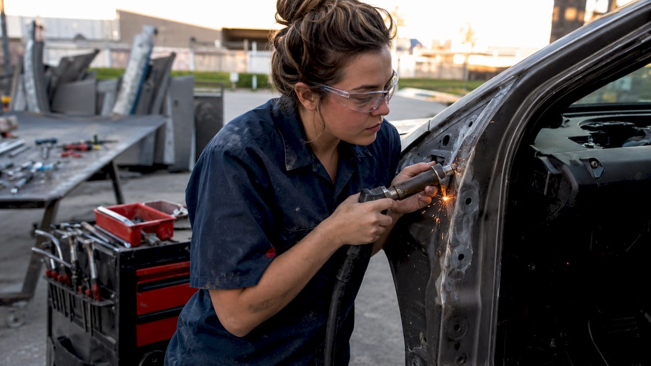 What Is Auto Body Refinishing? Your 2026 Guide 1 Technician Welding Car Door Frame In Workshop