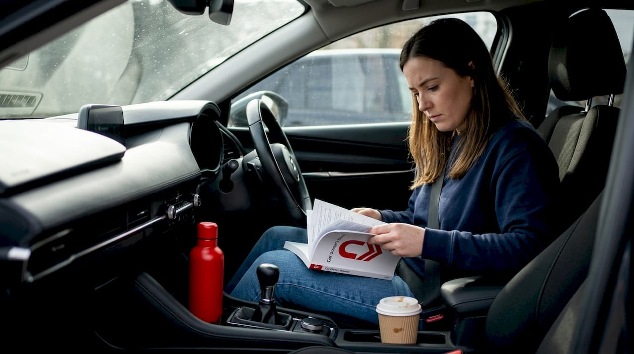 Woman checks oil type in car manual