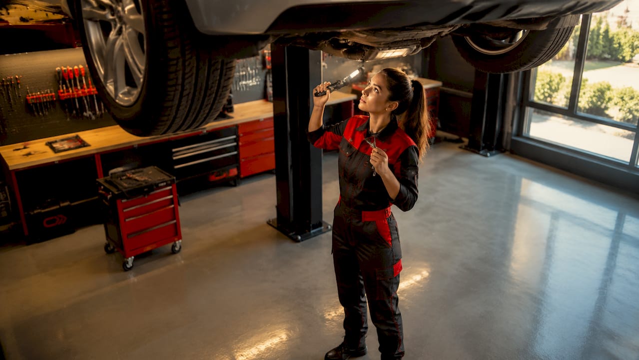Technician checking vehicle underside in service bay