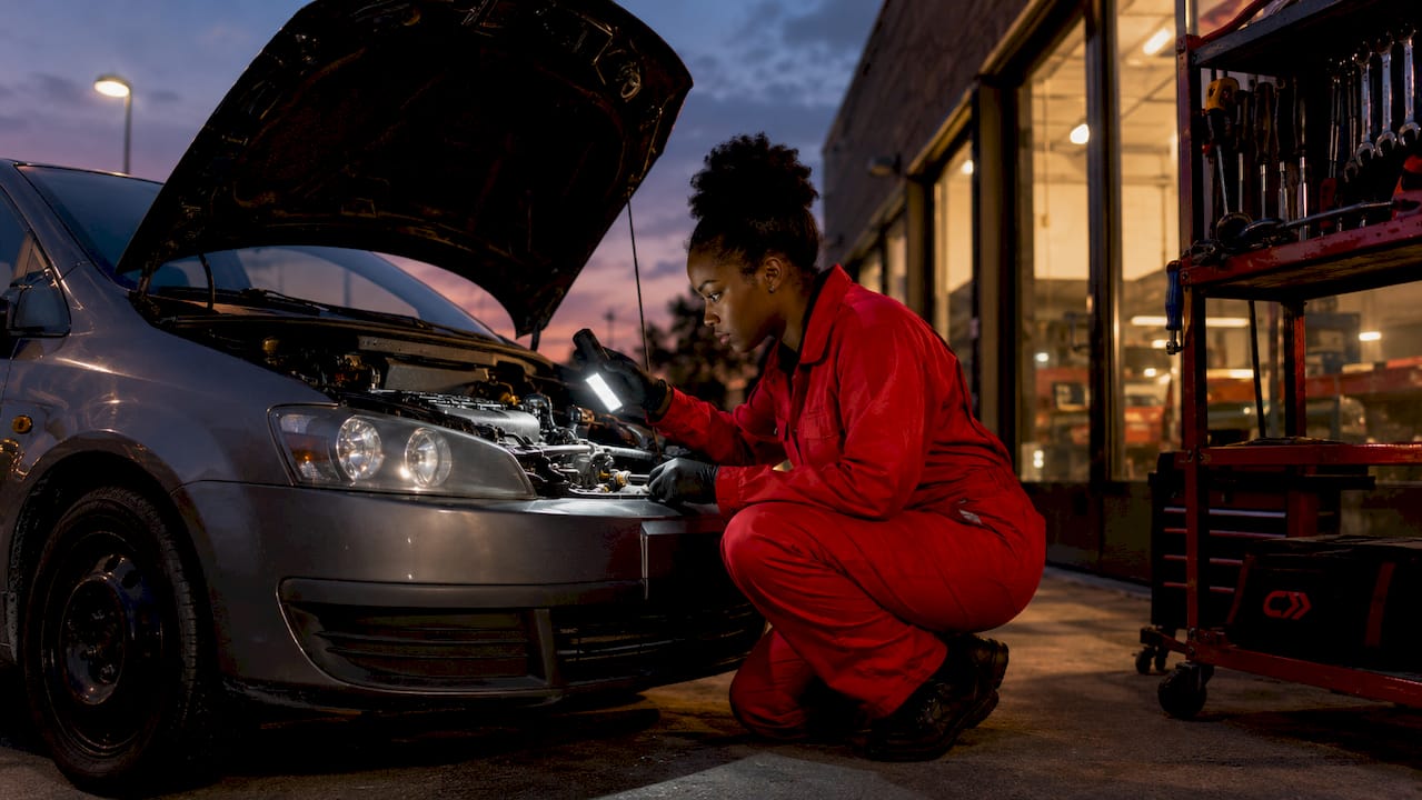 Mechanic inspecting car engine under hood