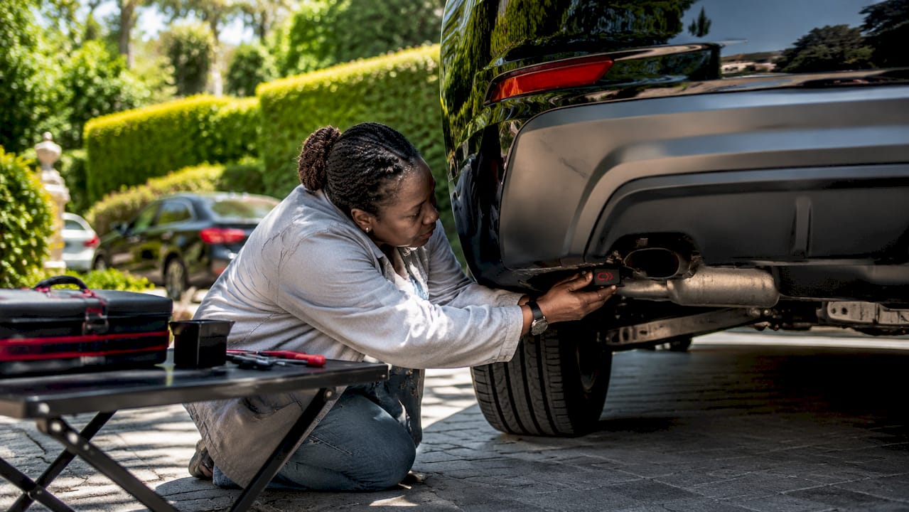 Technician installing GPS tracker on car