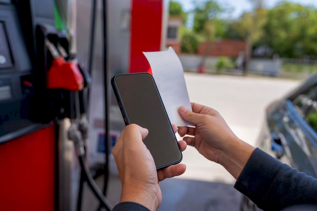 Hand photographing gas station receipt at fuel station