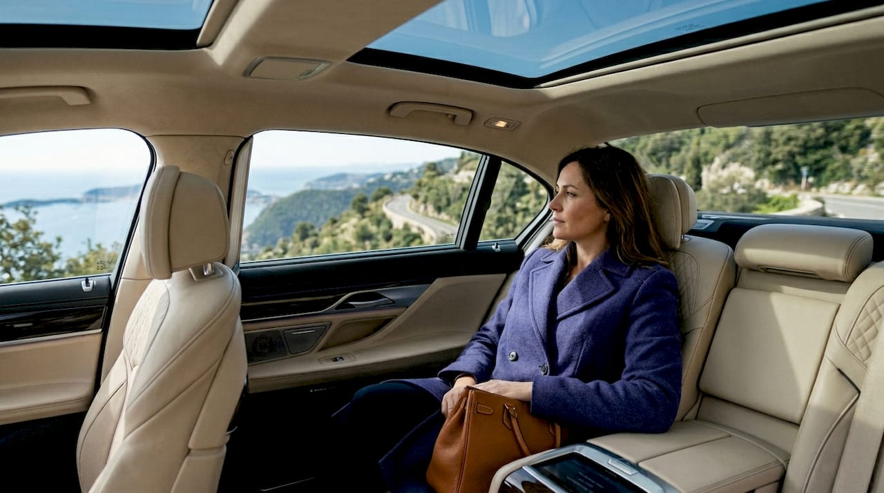 Une femme savoure la vue imprenable de la Côte d’Azur depuis le confort de sa voiture de luxe.