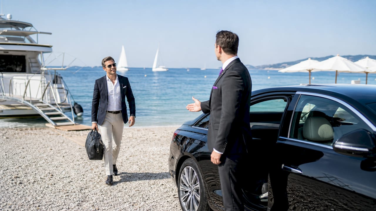 Le chauffeur ouvre la porte et aide l’homme d’affaires à prendre place dans la voiture de luxe.