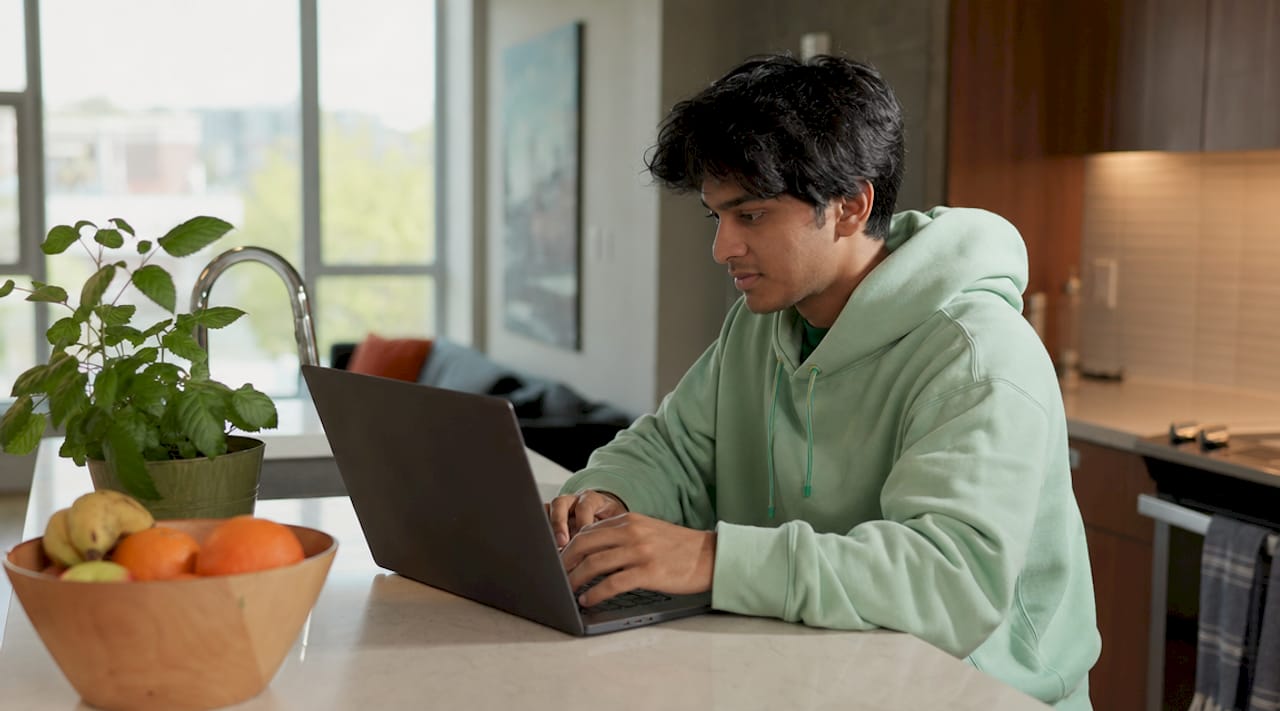 Hands typing on laptop at dorm desk