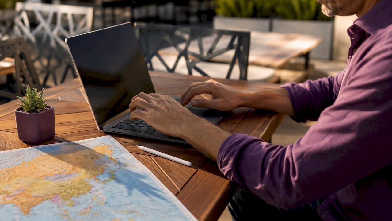 Hands typing with map and globe nearby