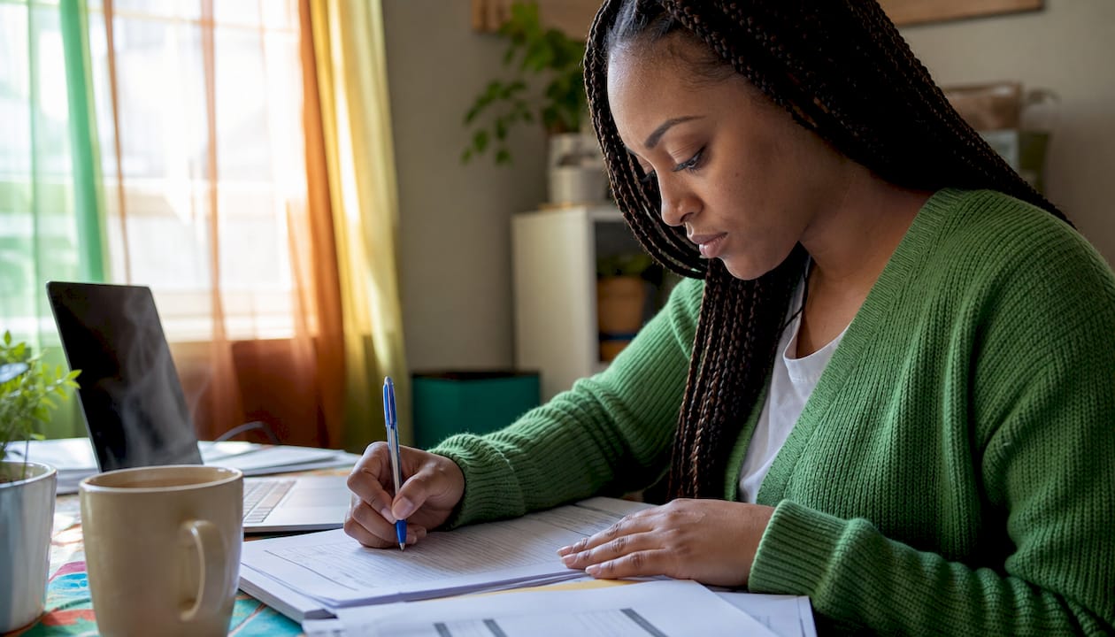 Woman completing loan repayment paperwork at kitchen table