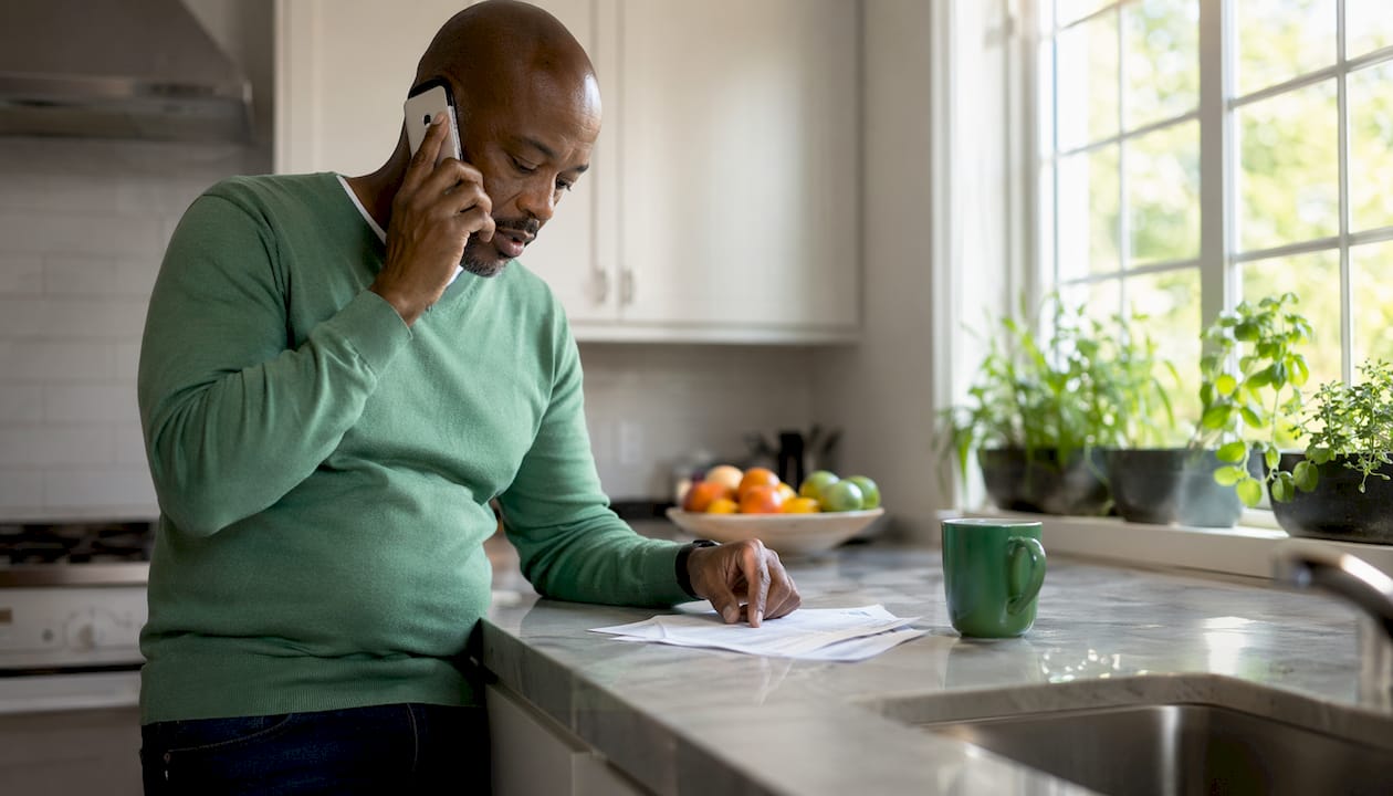 Man on phone reviewing loan paperwork in home office