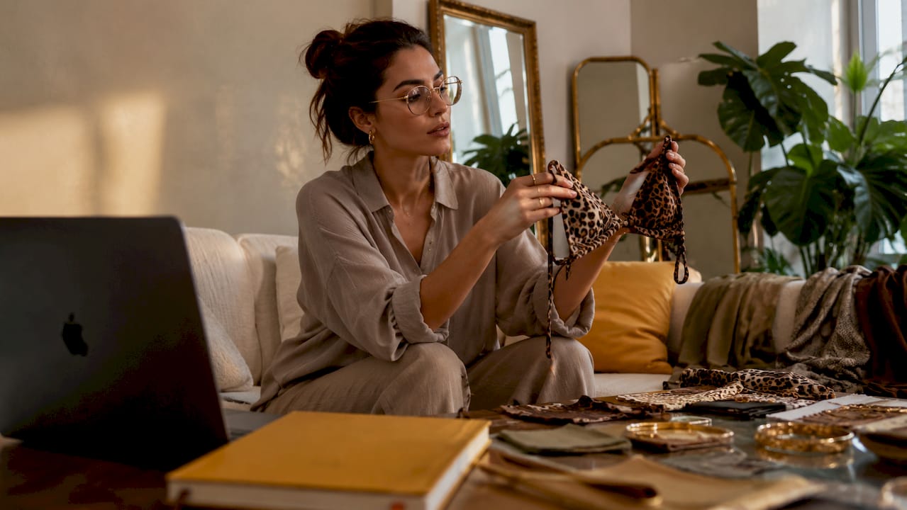Fashion stylist reviewing animal print bikini fabrics indoors