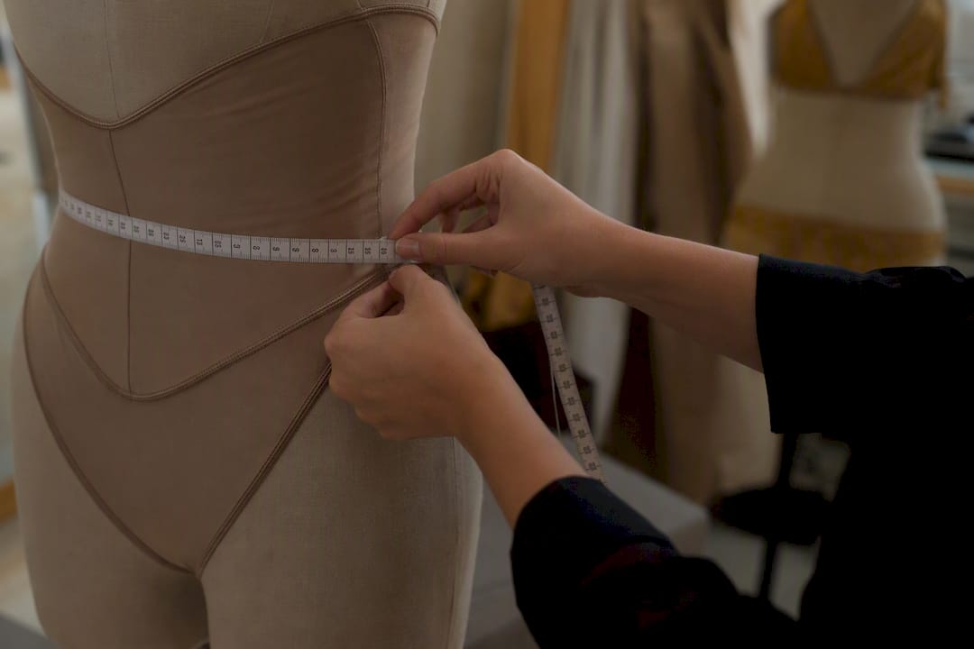 Measuring tape fitting swimwear fabric on mannequin