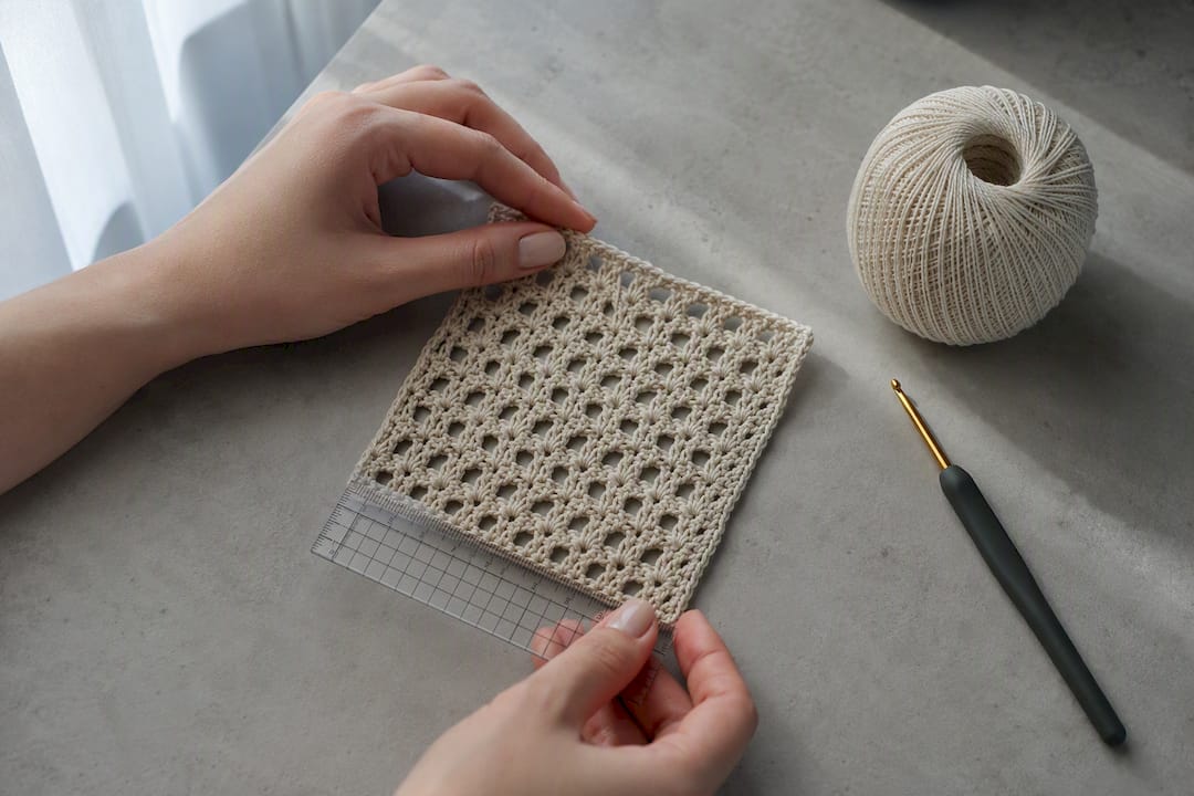 Hands measuring a crochet gauge swatch