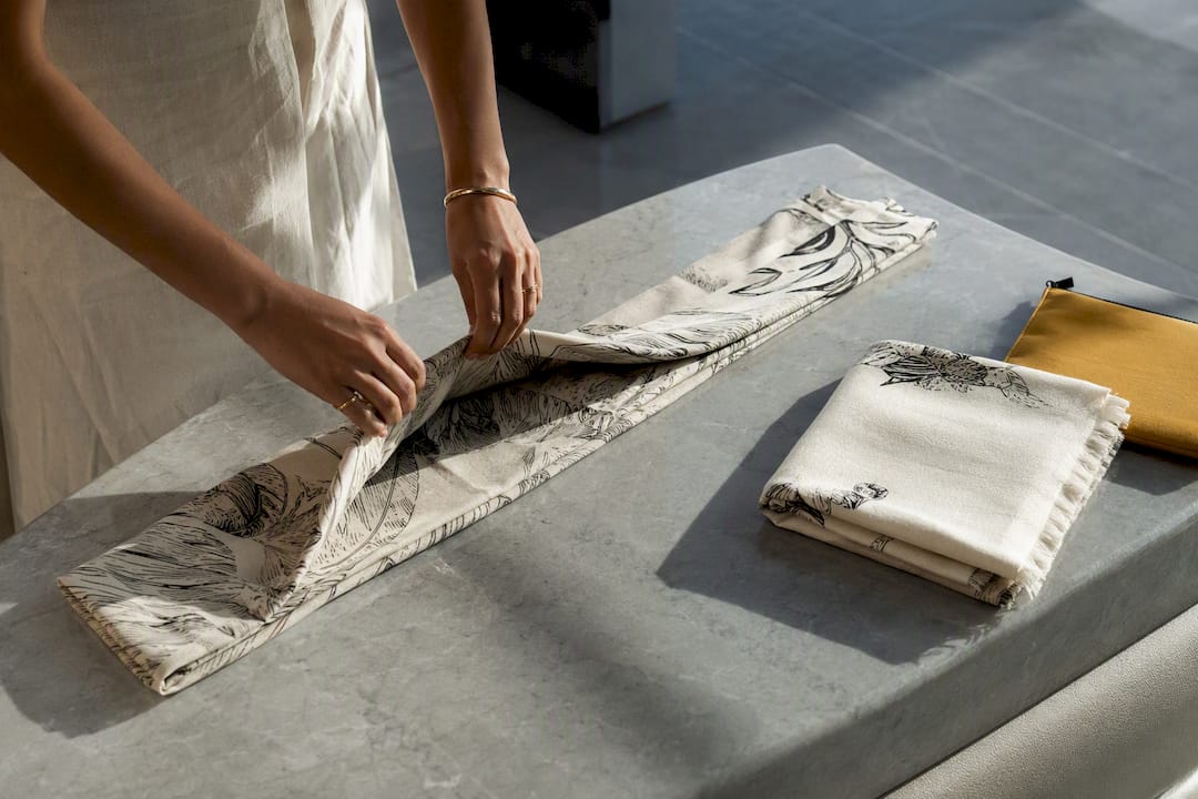Hands folding a sarong into a travel-ready strip