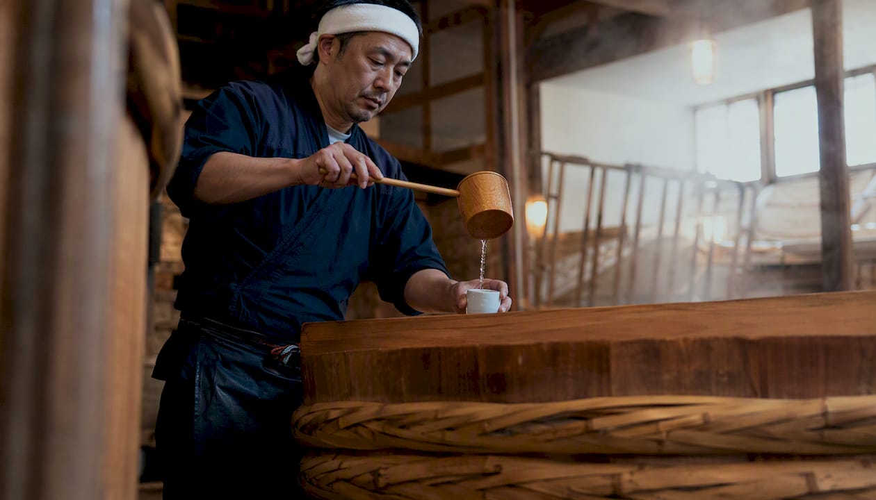 Sake brewer tasting batch in traditional brewery