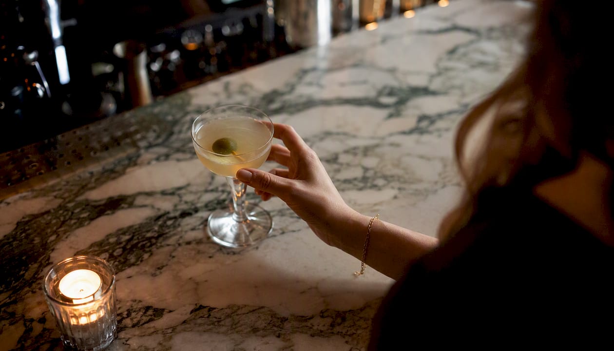 Hands reaching for cocktail on marble counter