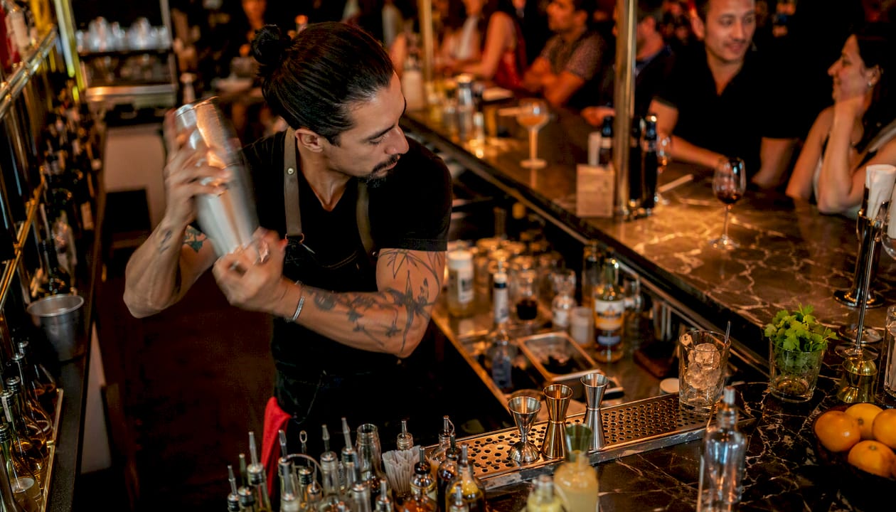 Bartender pouring cocktail at polished bar counter