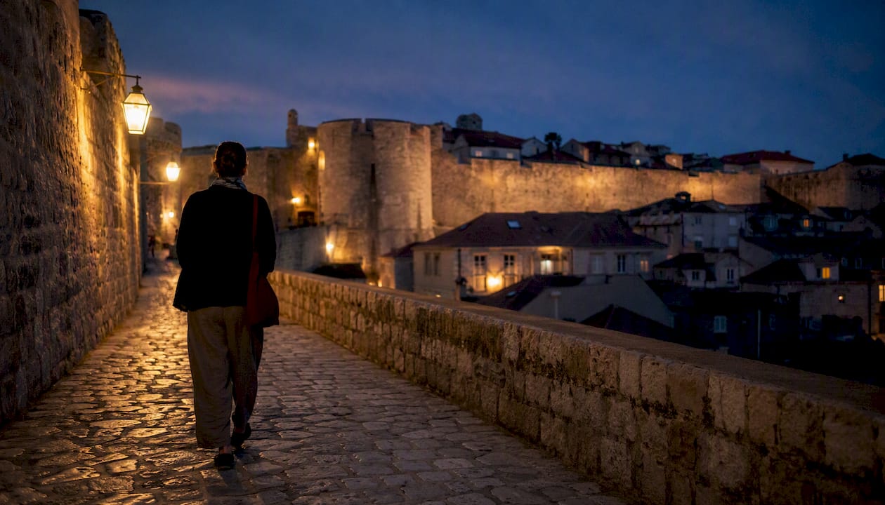 Traveler walking old city walls at dusk