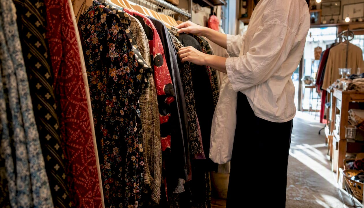 Hands browsing vintage denim jackets in shop