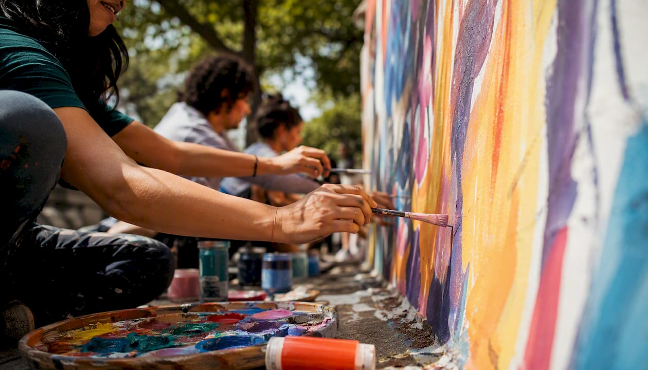 Hands painting community mural outdoors