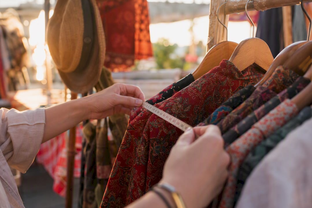 Hands measuring vintage clothing in boutique