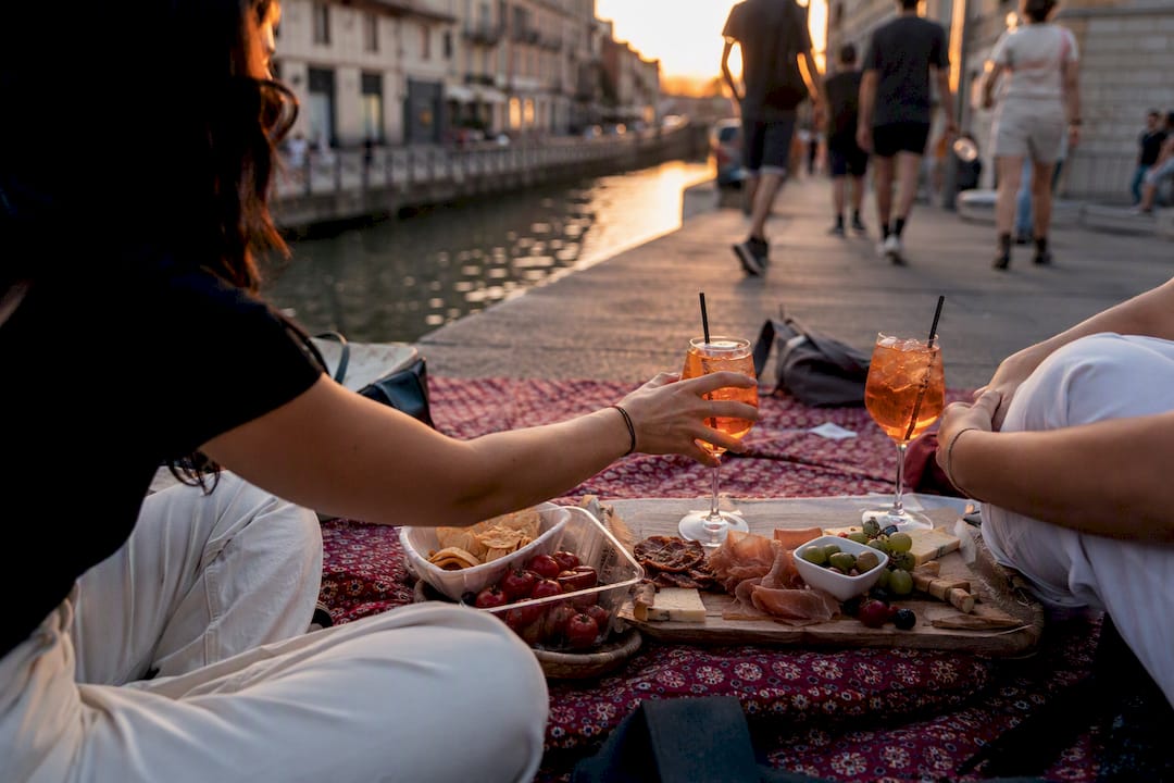 Pouring aperitivo drink beside Navigli canal at sunset