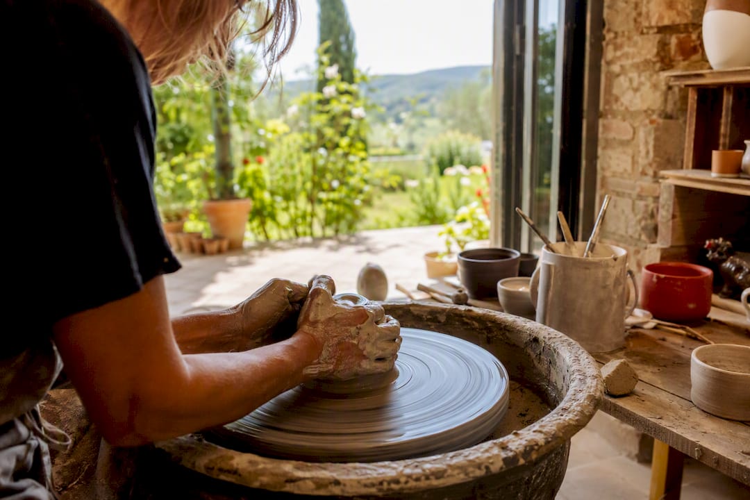 Hands shaping clay on pottery wheel