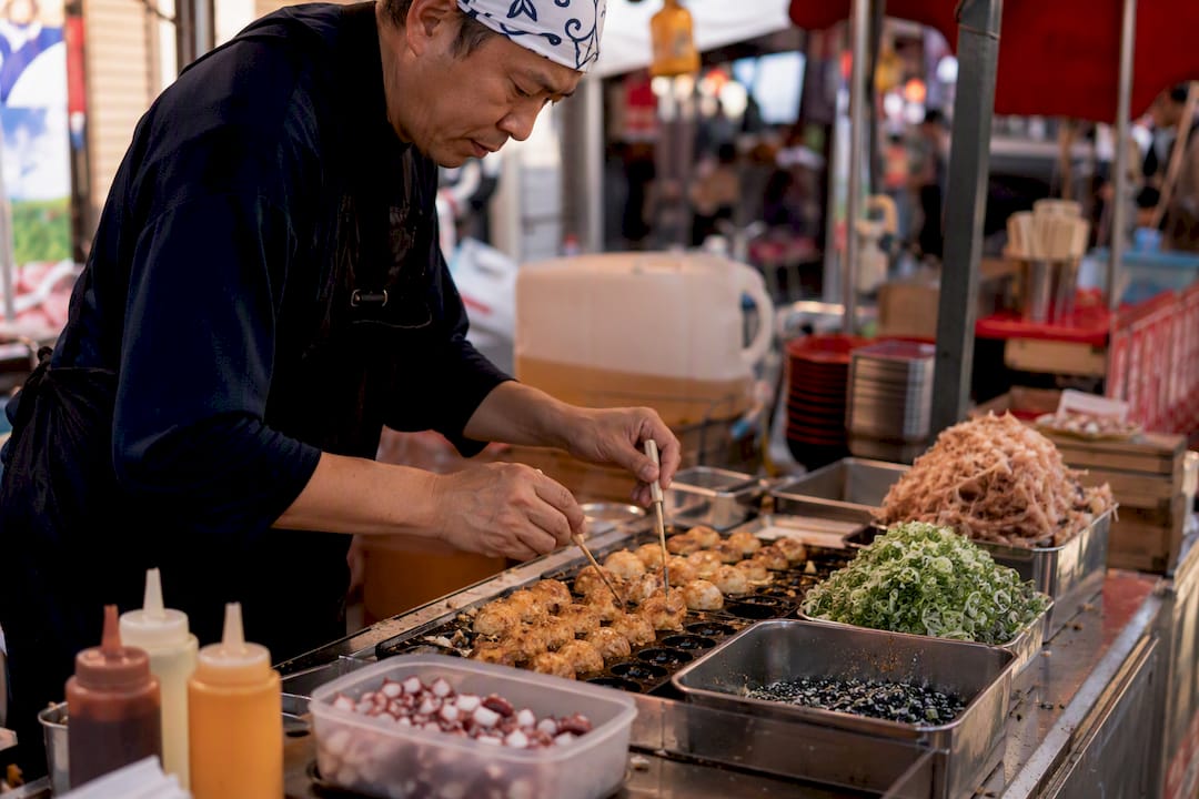 Cook flipping takoyaki balls on grill