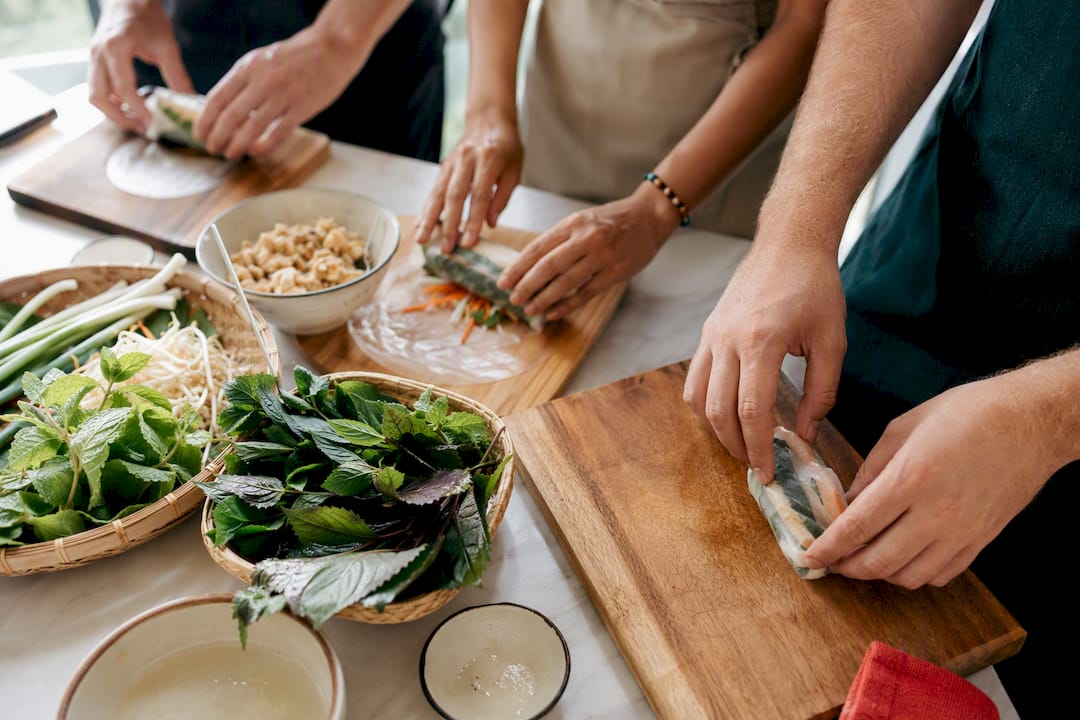 Travelers rolling spring rolls together