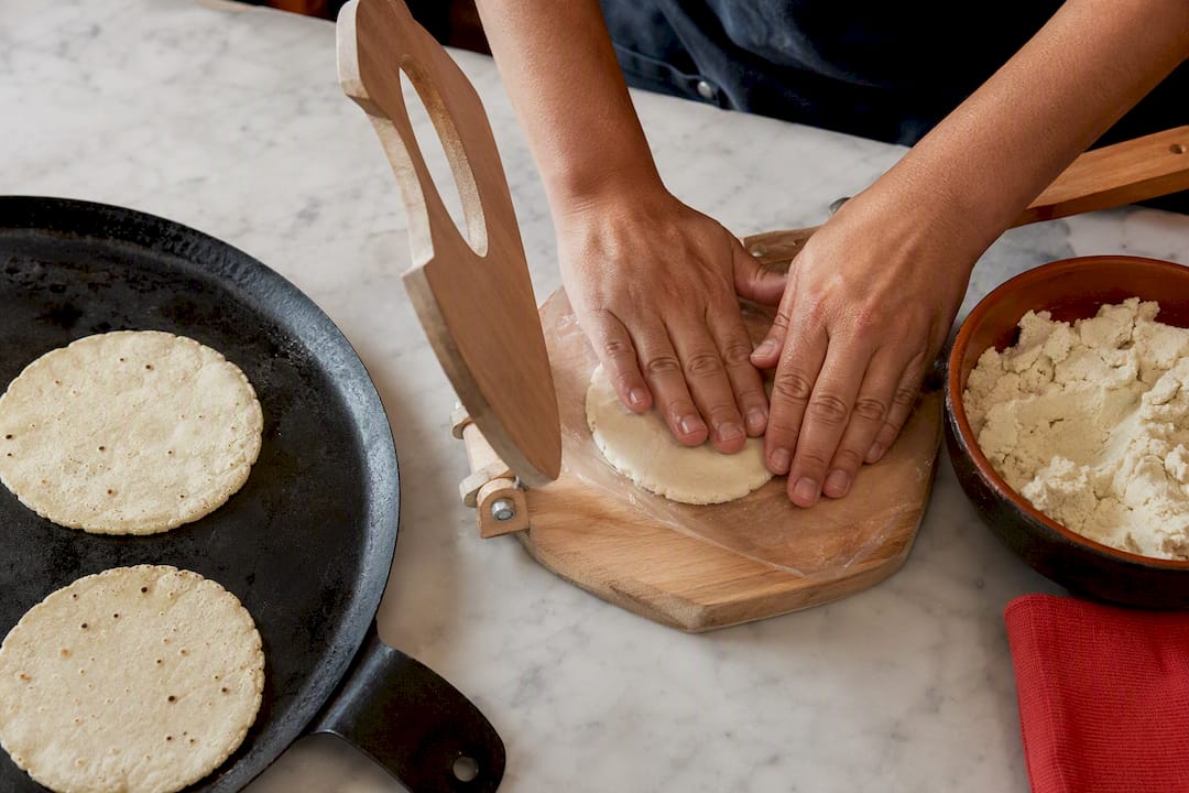 Hands pressing masa into a fresh tortilla
