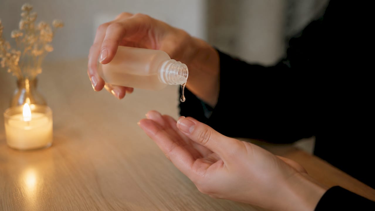 O mână care picură ser cosmetic pe vârful degetelor