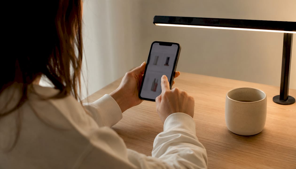 Prim-plan cu o persoană care compară prețurile produselor de îngrijire a pielii pe telefon.