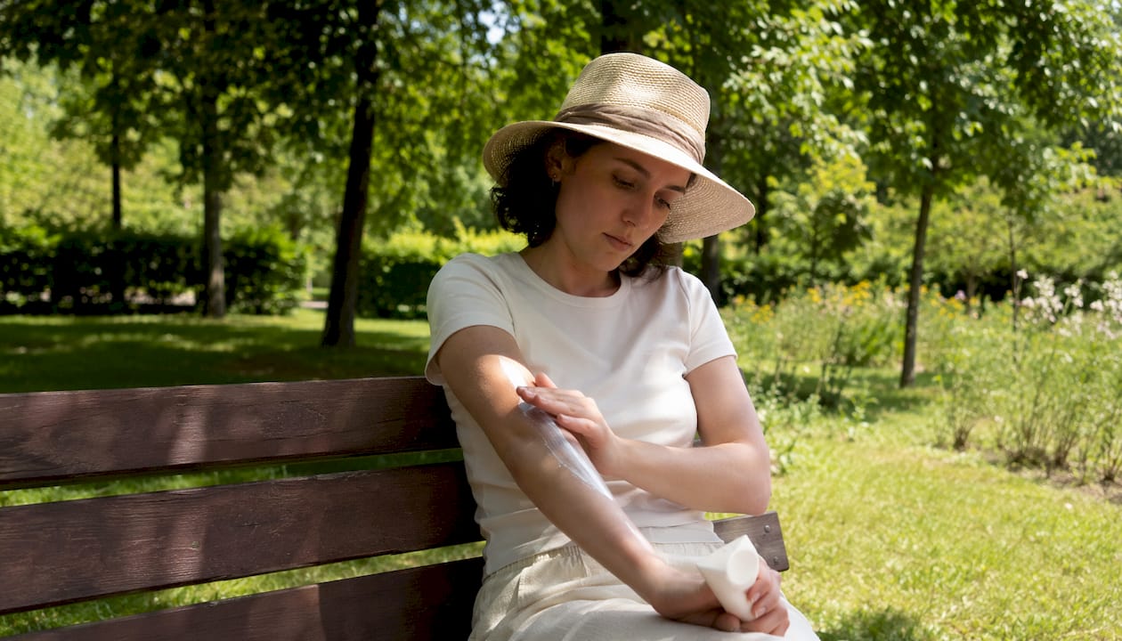 Mâini care întind cremă cu protecție solară pe piele