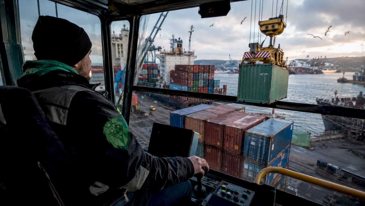 Busy UK port with container ships and crane operator