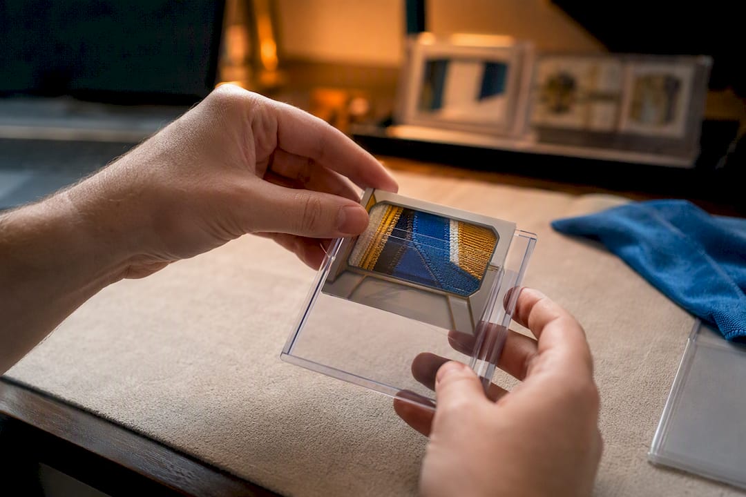 Hands placing thick relic card into clear top loader