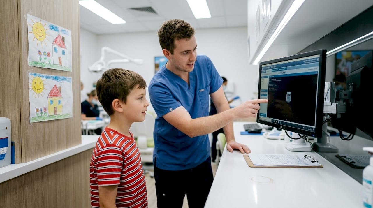 Dental assistant showing child digital x-ray machine