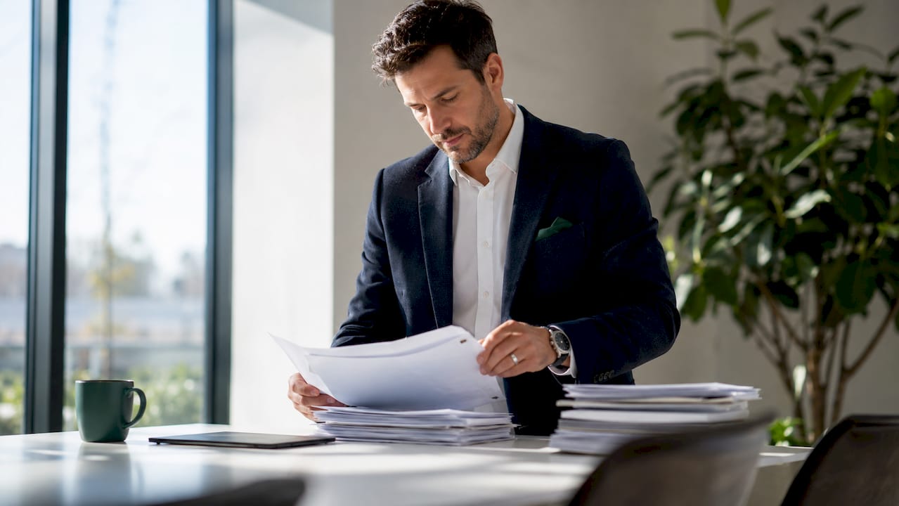 Hands organizing compliance policy documents at desk