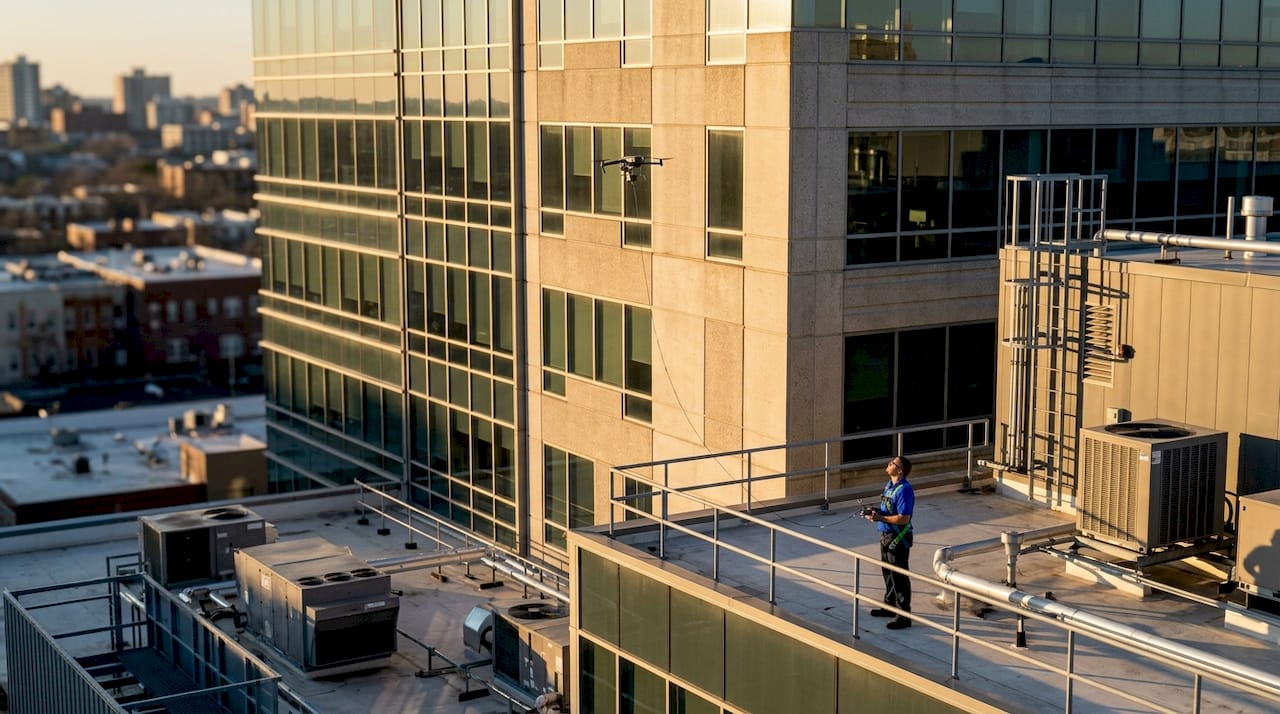 Drone inspecting commercial building facade from rooftop
