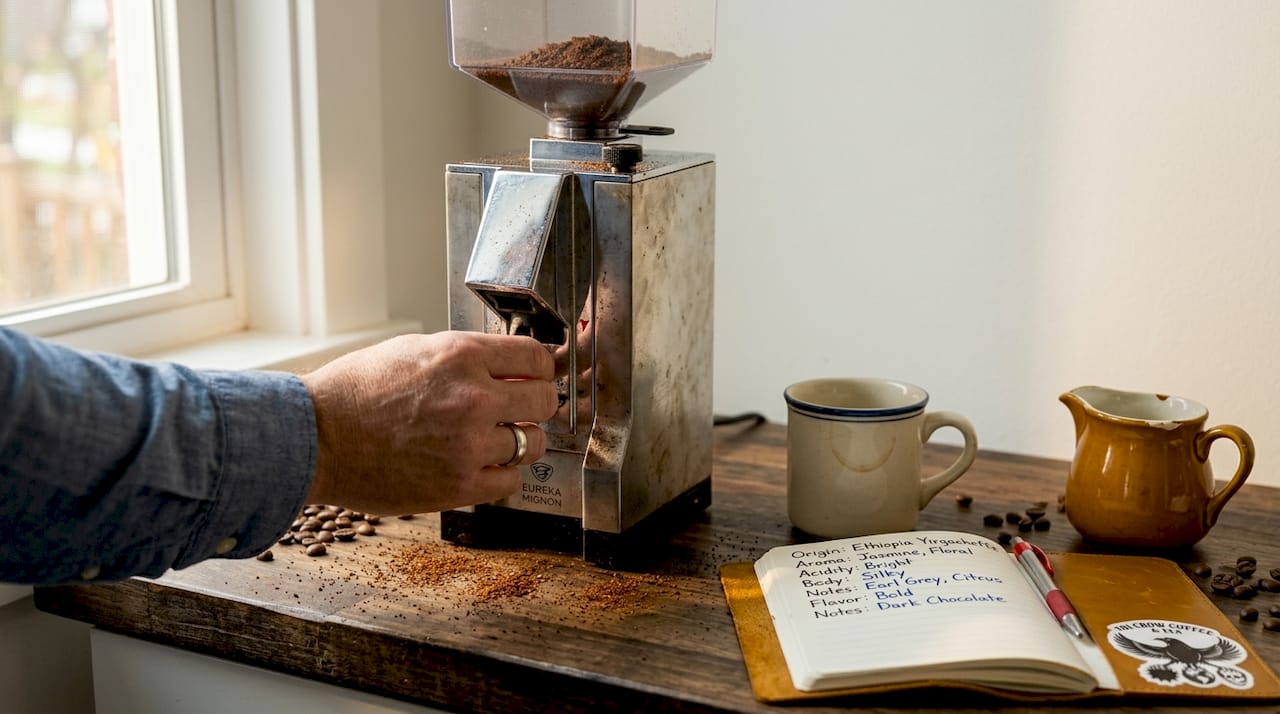 Hand adjusting burr coffee grinder in kitchen