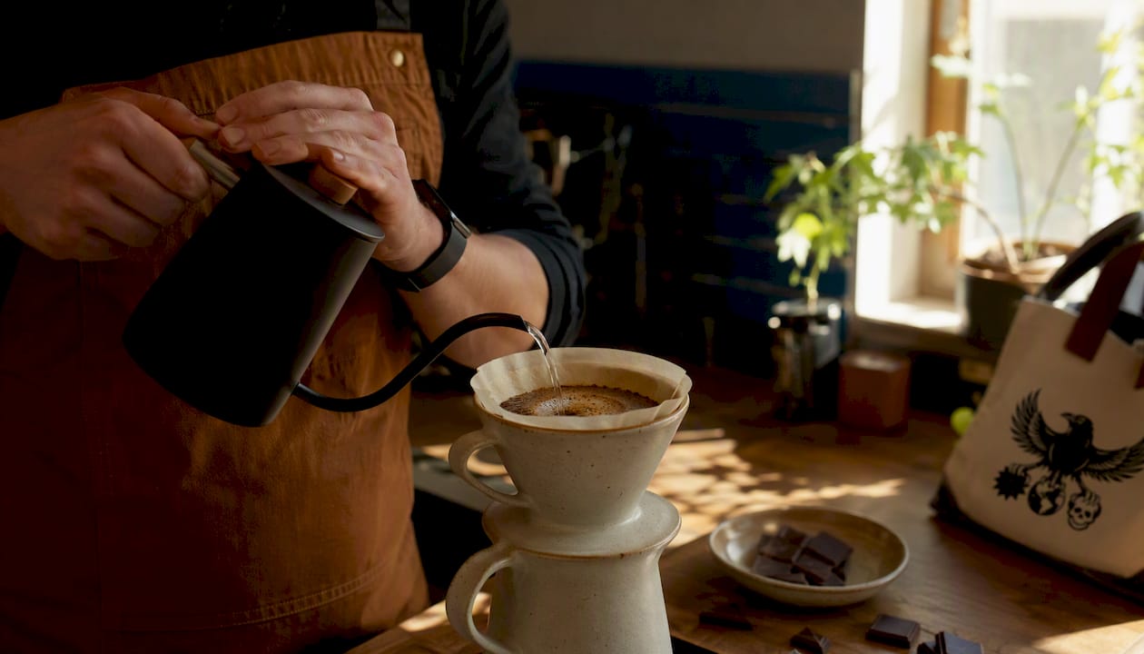 Hands pouring water over coffee grounds in pour-over