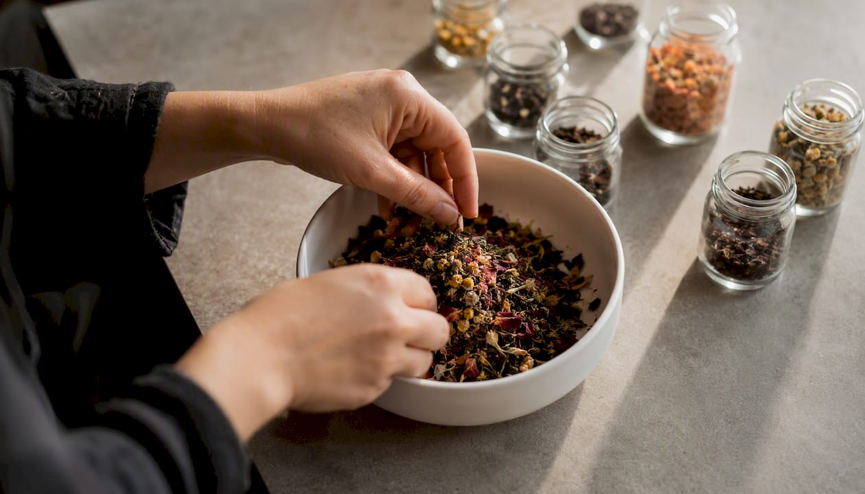 Hands mixing tea blend in a white bowl