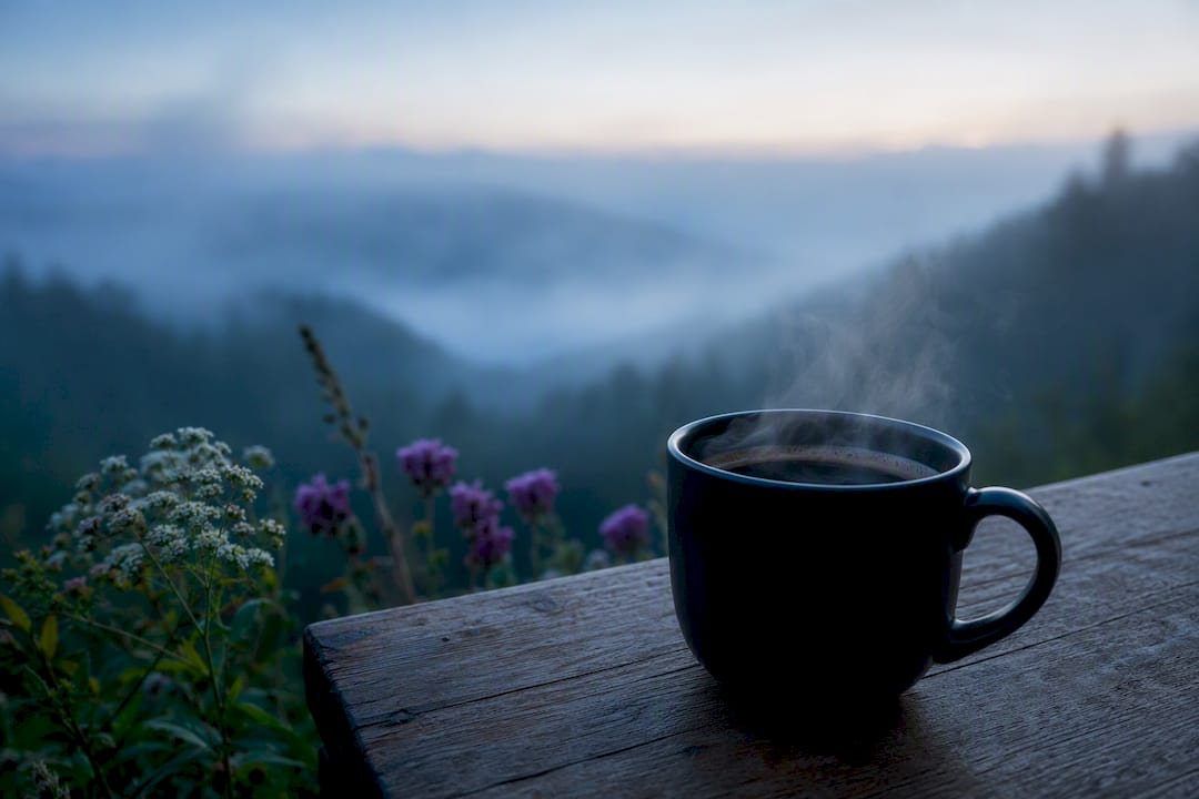 Steaming cup of black coffee on table