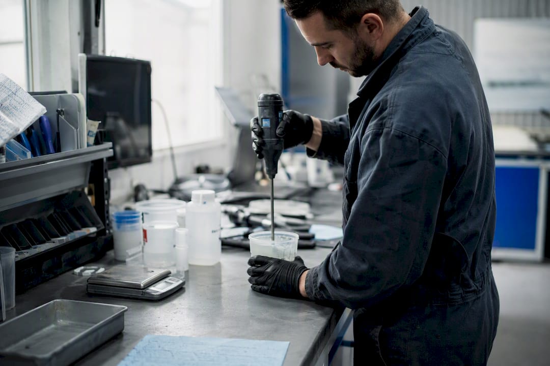 Mains du technicien en train de mélanger de la résine pour réparation de pare-brise